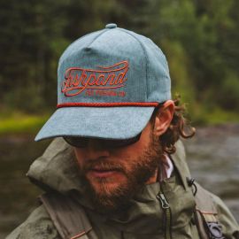 Nahaufnahme eines Anglers am Fluss, der die hellgrau-blaue Fishpond Cord-Kappe mit markantem orangefarbenem Schriftzug trägt